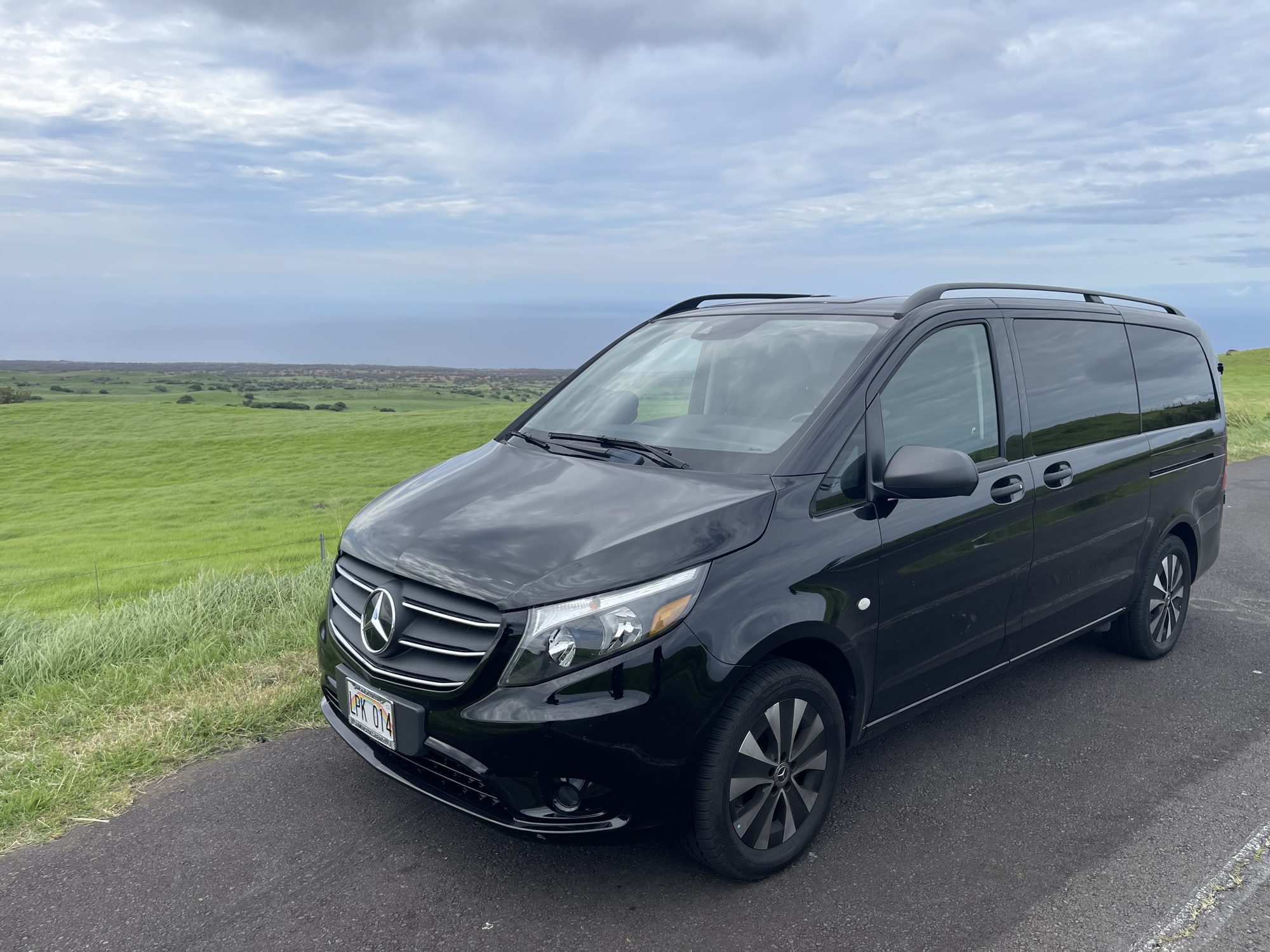 Black Mercedes-Benz Metris parked along a green Kohala pasture road